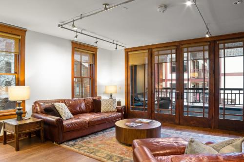 a living room with leather furniture and windows at Ballard North 202 - Ballard Bluebird in Telluride