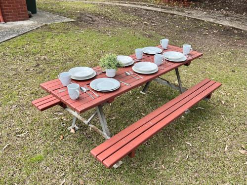 a picnic table with plates and cups and a bench at Cosy Room in North Ryde #2 in Sydney