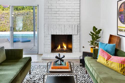 a living room with a couch and a fireplace at Mid Century Mood House by ACME House Company in Palm Springs
