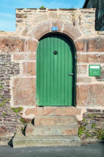 a green door on a brick building with steps at Maison Saint James in Saint-James