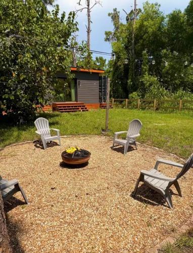 three chairs and a fire pit in a yard at Zen Container Tiny Home with Fenced-in Yard, Fire Pit, Centrally located and Pet Friendly in Fort Myers