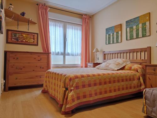 a bedroom with a bed and a dresser and a window at Ribadesella Centro, El trasiegu in Ribadesella