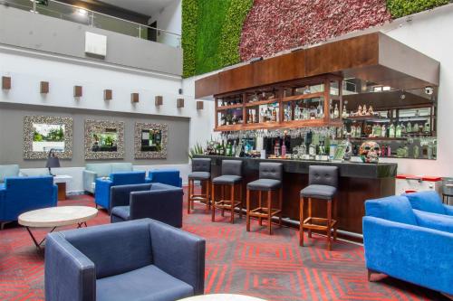 a lobby with blue chairs and a bar at Best Western Plus Santa Cecilia Pachuca in Pachuca de Soto