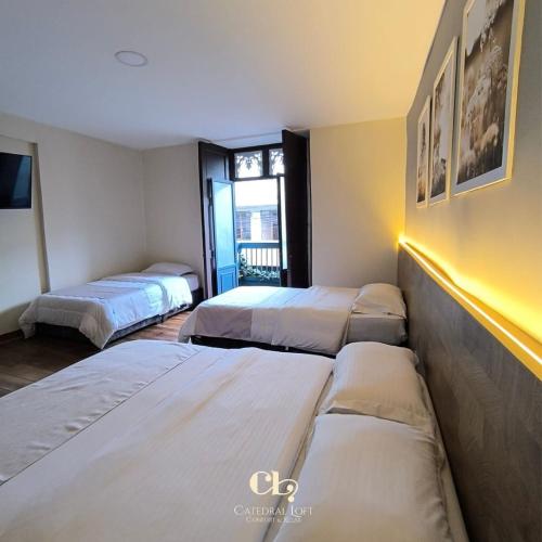 a room with three beds and a window at Hotel Catedral Boutique Loft in Pasto