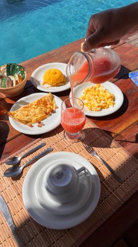 a table with plates of food and a pitcher of juice at Kamaiurá Pousada in Caraíva