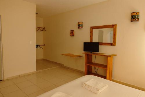a room with a bed and a mirror and a television at Guest house La Casa del Quetzal in Mérida