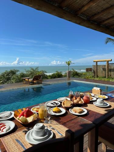 a table with food on it next to a swimming pool at Kamaiurá Pousada in Caraíva