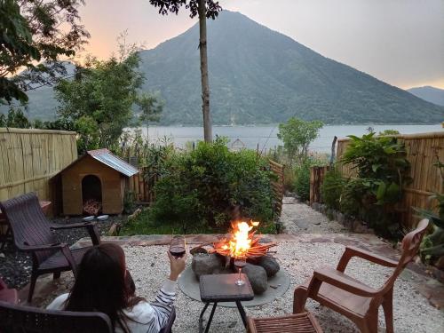a woman is sitting around a fire in a backyard at Luxe A-Frame on Lake Atitlán in Santiago Atitlán