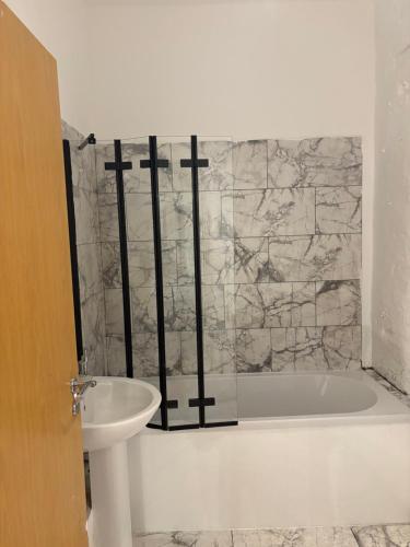 ein Badezimmer mit Badewanne und Waschbecken in der Unterkunft 3 Bed Luxury Contractors Apartment, Free Parking, City Centre, Fast WiFi by Opulent Stays in Derby