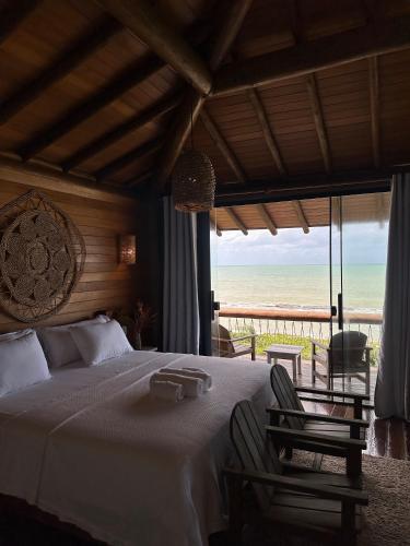 a bedroom with a bed and a view of the beach at Kamaiurá Pousada in Caraíva