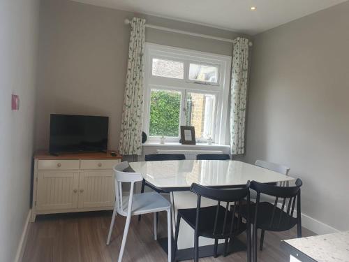a dining room with a table and chairs and a window at Place to Stay in Thames Ditton in London