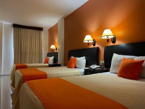 a hotel room with two beds with orange pillows at Hotel Baez Paraiso in Paraíso