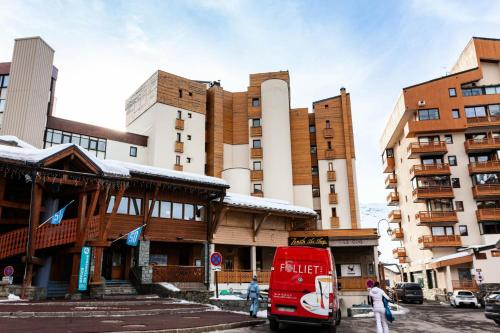 a red bus is parked in front of a building at Résidence Zenith - SKIS AUX PIEDS POUR CE STUDIO 3 PERSONNES MAE-7753 in Val Thorens