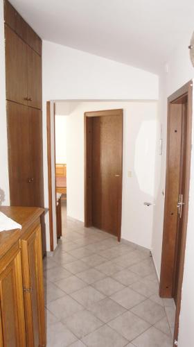 a kitchen with a hallway with wooden cabinets and a door at Suran Apartments in Pula