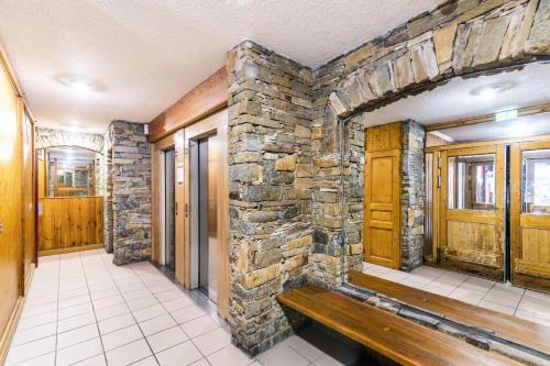 a stone wall in a hallway with a wooden bench at Résidence Arcelle - VAL THORENS location: studio cabine en plein centre de la station MAE-9104 in Val Thorens