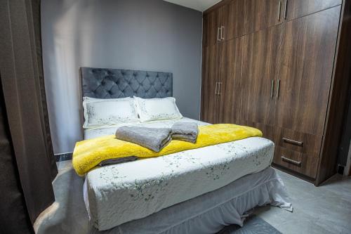 a bedroom with a bed with a yellow blanket at Nkachika Apartments in Lusaka