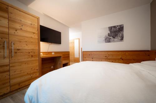 a bedroom with a white bed and a television at Hotel Garni Arnica ***S in Madonna di Campiglio