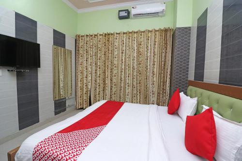 a bedroom with a bed with red and white pillows at Hotel O Rajshree in Sonīpat