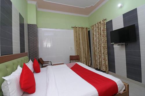 a bedroom with a bed with red pillows and a flat screen tv at Hotel O Rajshree in Sonīpat