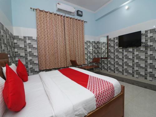 a bedroom with a bed with red pillows and a television at Hotel O Rajshree in Sonīpat
