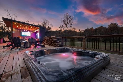 a jacuzzi tub on a deck with a television at Creekside Oasis - 5BR Retreat with Pool & Hot Tub in Rogers