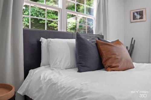 a bed with white sheets and pillows in front of a window at Creekside Oasis - 5BR Retreat with Pool & Hot Tub in Rogers