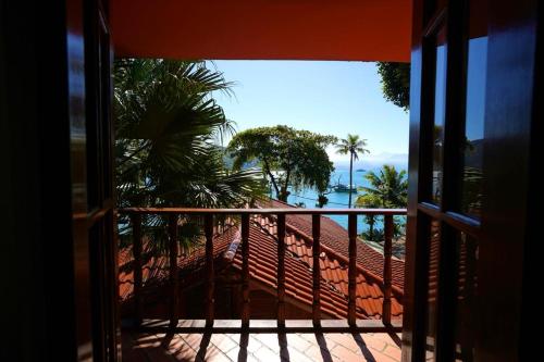 a balcony with a view of the ocean and palm trees at Casa da Ilha & SPA in Abraão