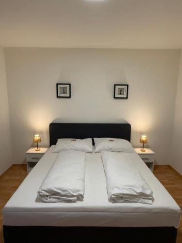 a large bed with two nightstands and two pictures on the wall at Airport Apartment Rauchenwarth in Rauchenwarth
