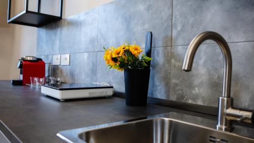 a kitchen counter with a sink and a vase of yellow flowers at Suites 215 Colosseum - Guesthouse in Rome