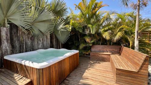 a hot tub on a deck with a bench and palm trees at Chalet Monte Boa Vista - Aconchego na Serra com Hidromassagem Exclusiva in Teresópolis