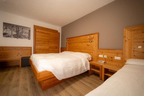 a bedroom with two beds and wooden walls at Hotel Garni Arnica ***S in Madonna di Campiglio