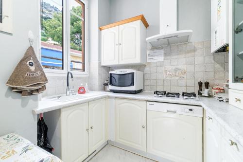 a kitchen with white cabinets and a microwave at La Terrasse de Bracco in Beaulieu-sur-Mer