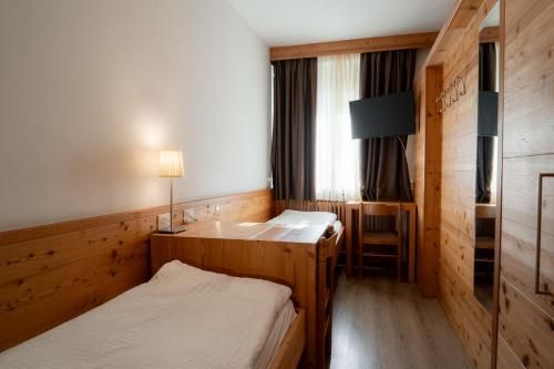 a small room with two beds and a window at Hotel Garni Arnica ***S in Madonna di Campiglio