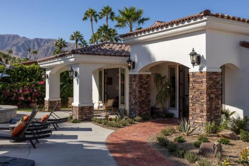 une maison blanche avec une terrasse et des chaises dans l'établissement Mirador Desert Oasis by ACME House Company, à Palm Springs