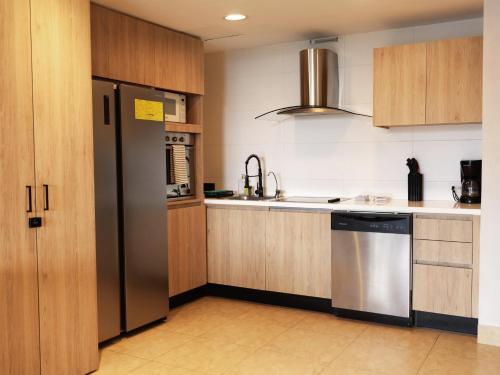 a kitchen with wooden cabinets and a stainless steel refrigerator at Beach Apartment At Nikki Residences 2 Bedroom in El Chirú