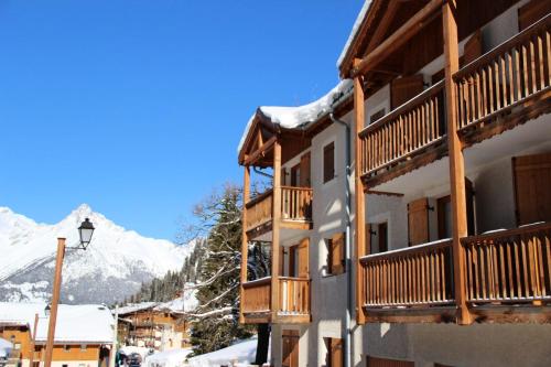 a building with wooden balconies and a snow covered mountain at Résidence Belvedere Busseroles - RESIDENCE LE BELVEDERE "BUSSEROLES" - BELVB12 MAE-3102 in Modane