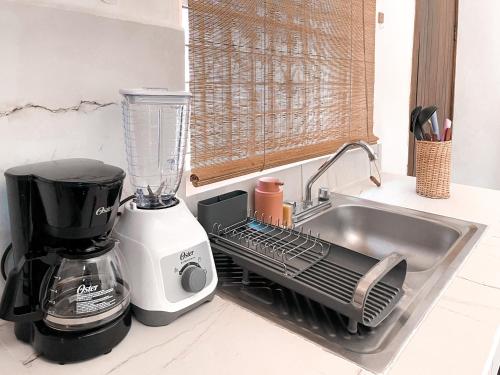a kitchen sink with a dish drying rack next to a blender at Cocoa by Casa Momo Apartamento Acogedor y Céntrico in Bacalar
