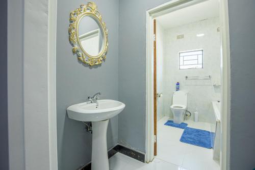 a bathroom with a sink and a mirror and a toilet at Nkachika Apartments in Lusaka