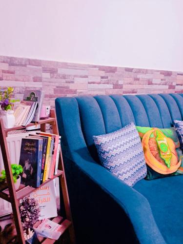 a blue couch with pillows and books in a room at شقة مميزة in Rujm Maghghijhah