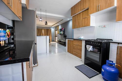a kitchen with black appliances and wooden cabinets at Nkachika Apartments in Lusaka
