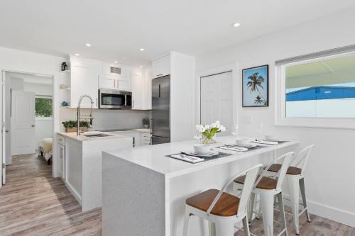 a white kitchen with a large white island with stools at Location & Comfort- Coastal Meets Contemporary in Vero Beach