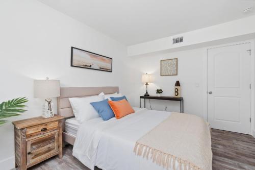 a bedroom with a white bed with orange and blue pillows at Location & Comfort- Coastal Meets Contemporary in Vero Beach
