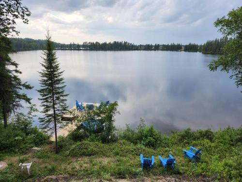 a group of chairs sitting on the shore of a lake at La Belle Vie in Saint Ludger de Milot