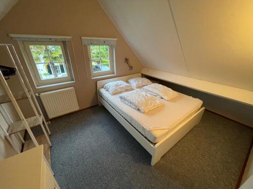 a bedroom with a bed with two pillows and a ladder at Freistehendes Ferienhaus am See Nähe Roermond in Heel