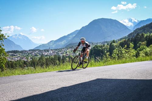 a man riding a bike down a road at Apart Bieles NEU - Bergoase mit privater Outdoor-Sauna & Massagepraxis in Kauns