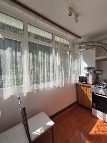 a kitchen with white curtains and a table and a stove at Apartament Verde Residence Slănic-Moldova in Slănic-Moldova