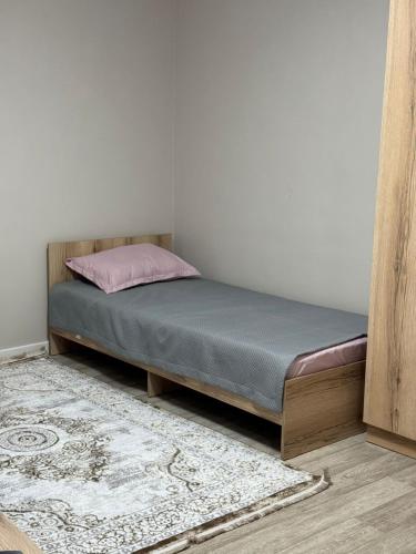 ein Schlafzimmer mit einem Bett mit einem rosa Kissen und einem Teppich in der Unterkunft Фучика 50 in Zhezdi