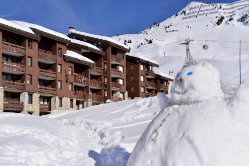a snow man standing in the snow in front of a building at Résidence Pierre De Soleil - Studio cosy · Skis aux pieds MAE-3617 in Mâcot La Plagne