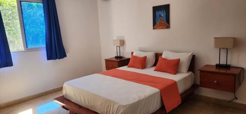 a bedroom with a bed with orange and white pillows at Bella Villa Roomy apartment at 5 min walk to the beach in Las Galeras
