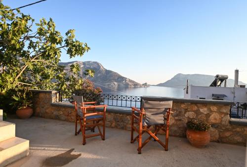 a patio with two chairs and a table with a view of the water at Skalia Mountain & Sea Suites in Skaliá